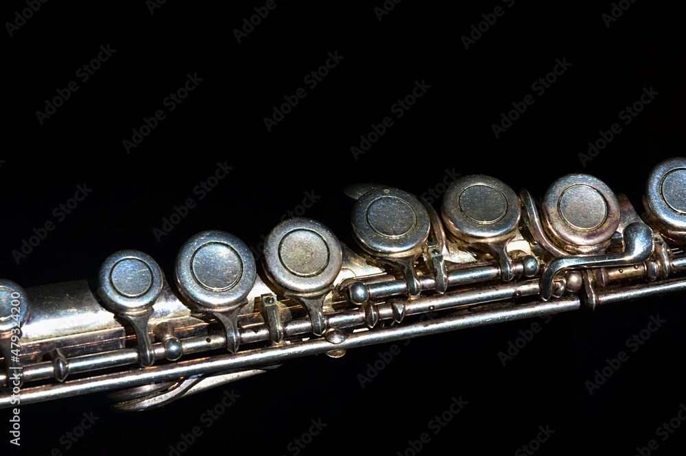 Fototapeta premium Detail of partially oxidized middle joint of older silver coated transverse flute musical instrument, visible signs of use and corrosion, dark background. 