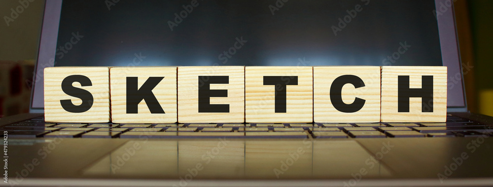 Obraz premium Word SKETCH. Wooden cubes with letters isolated on a laptop keyboard. Business Concept.