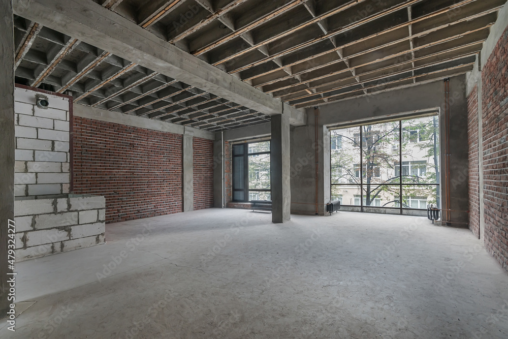 A spacious room without decoration with brick walls and large windows.
