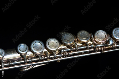 Canvas Print Detail of partially oxidized middle joint of older silver coated transverse flute musical instrument, visible signs of use and corrosion, dark background