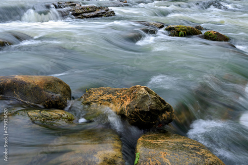 Mountain river with rocks at a long exposure from the bottom of the photograph