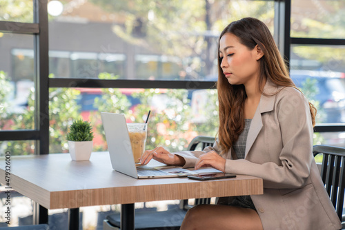 Businesswoman wearing suit and looking at laptop sitting in the coffee shop with a cup of ice coffee. Shopping online with credit card, freelancer, internet. Business and shopping concept Free Download Businesswoman wearing suit and looking at laptop sitting in the coffee shop with a cup of ice coffee. Shopping online with credit card, freelancer, internet. Business and shopping concept - GFXLoad