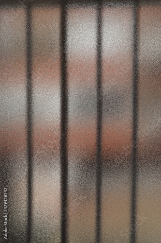 Opaque window of a balcony where you can see some bars and sunlight from outside photo