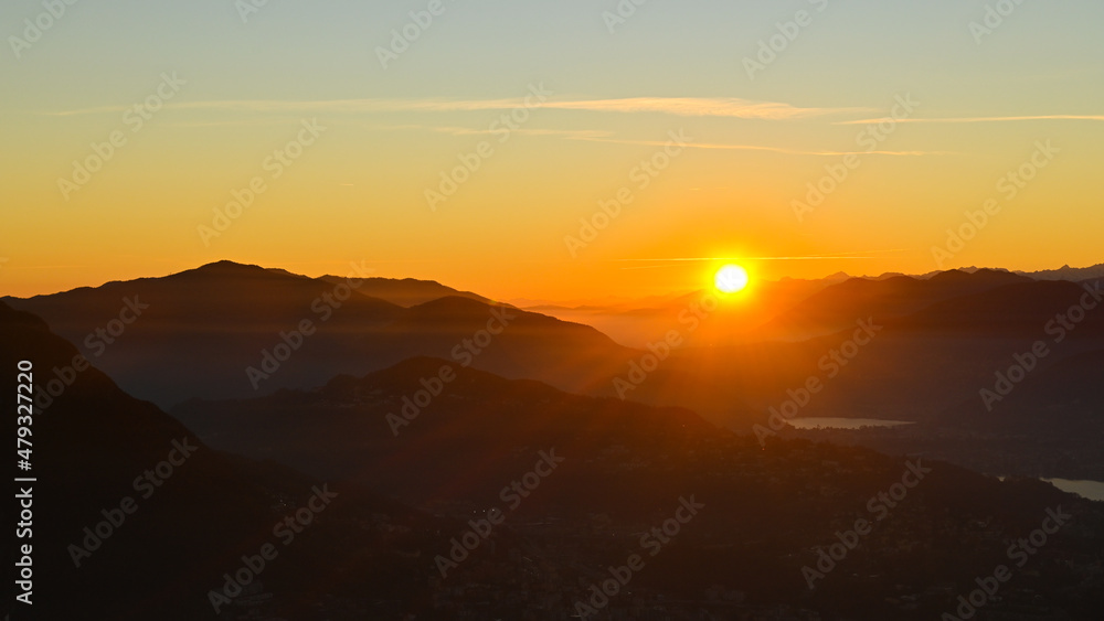 Sole che tramonta sopra il lago, bellissimo momento nel mese di ottobre, con scia dorata sopra le montagne