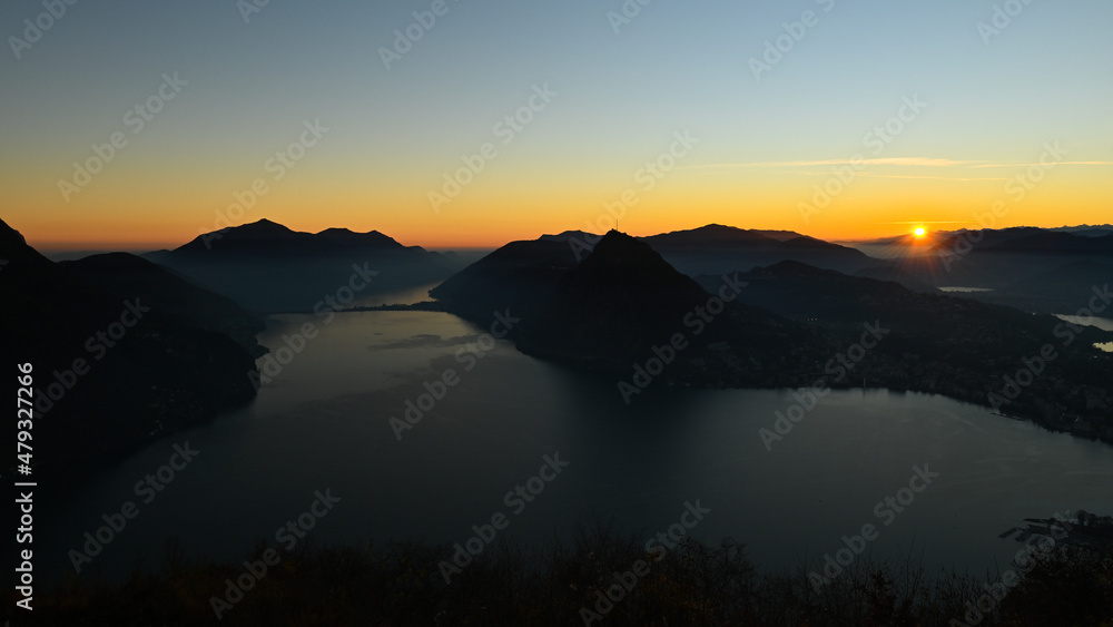 Sole che tramonta sopra il lago, bellissimo momento nel mese di ottobre, con scia dorata sopra le montagne Sole che tramonta sopra il lago, bellissimo momento nel mese di ottobre, con scia dorata sopra le montagne