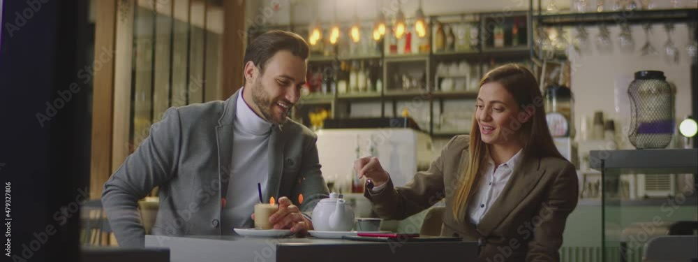 Adult Caucasian couple spending time in retro style cafe. Sitting at small table, drinking tea or coffee and speaking together. Adult Caucasian couple spending time in retro style cafe. Sitting at small table, drinking tea or coffee and speaking together.