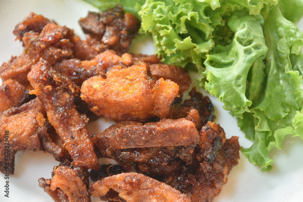 crispy fried pork belly with chili sauce and lettuce on plate