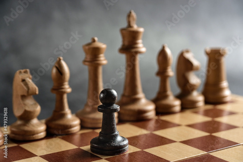 The black chess pawn opposes the white pieces. The concept of struggle  conflict  overcoming.