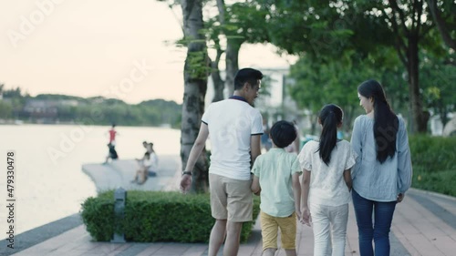 rear view of Asian family parents and kids walking on waterfront promenade