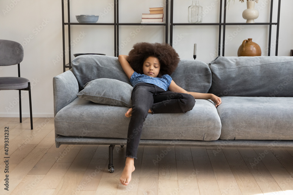Peaceful calm cute African girl kid with curly hair resting on comfortable couch in living room, sleeping. Tired asleep child drowsing at daytime, taking nap, relaxing on sofa at home. Peaceful calm cute African girl kid with curly hair resting on comfortable couch in living room, sleeping. Tired asleep child drowsing at daytime, taking nap, relaxing on sofa at home.