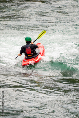 River kayaker in red kayak are paddling whitewatered river. Extreme sports and adrenaline concept. Removed logos. © Jon Anders Wiken