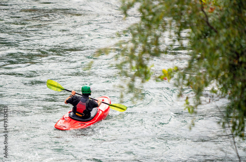 River kayaker in red kayak are paddling whitewatered river. Extreme sports and adrenaline concept. Removed logos.