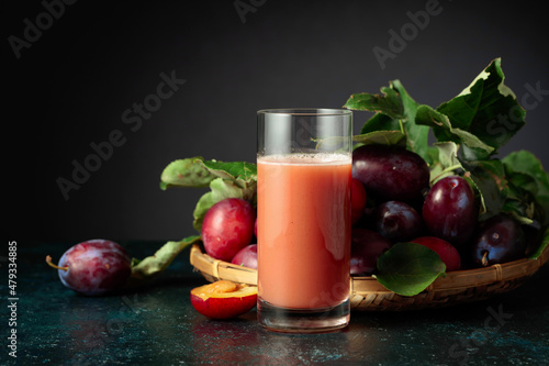 Plum juice and fresh purple plums.