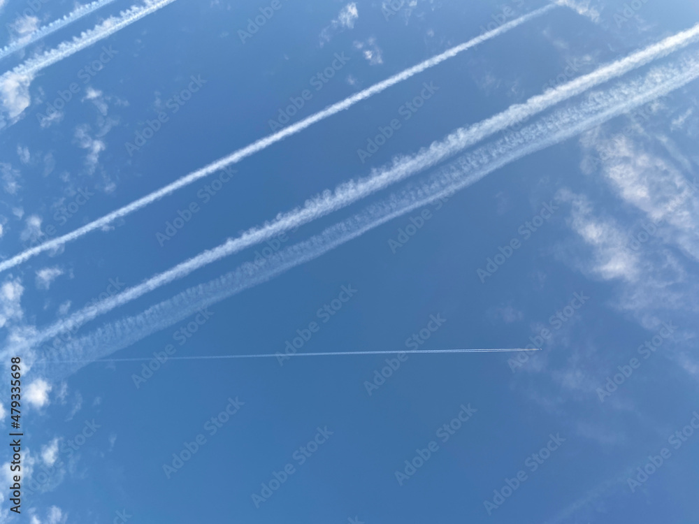 Airplane in the blue sky with clouds from below. High flying passenger ...