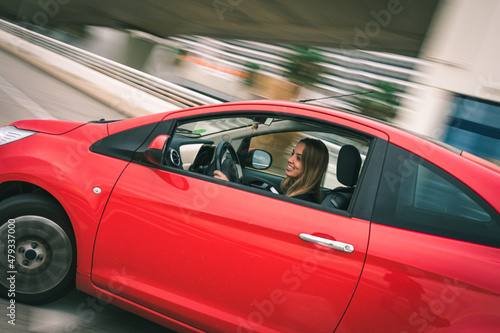 Young girl enjoying driving her little red car