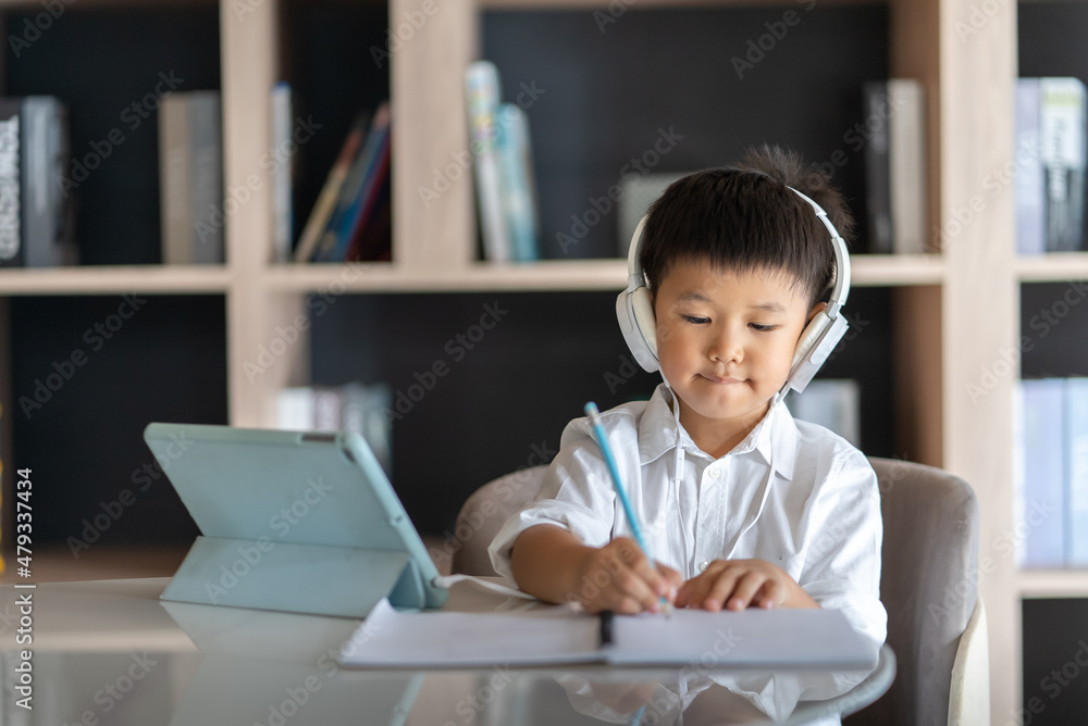 Asian boy study online with digital tablet and headphone. Concept of online studying & home school Asian boy study online with digital tablet and headphone. Concept of online studying & home school