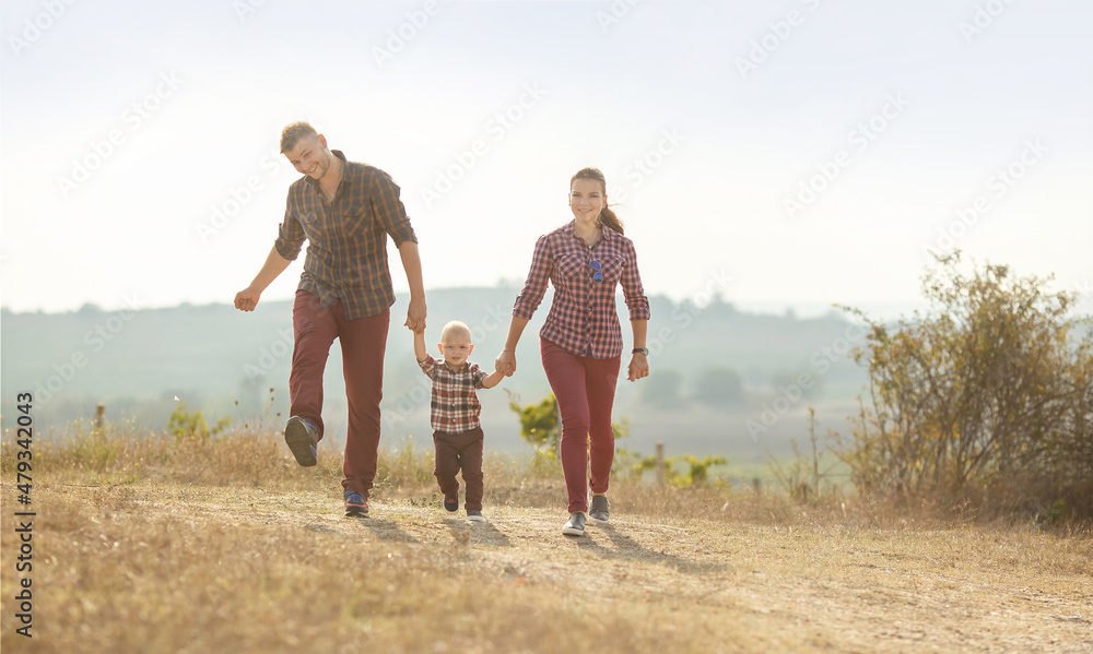 a young woman , a man and a little boy are having fun holding hands in a vineyard . They are dressed in plaid shirts a young woman , a man and a little boy are having fun holding hands in a vineyard . They are dressed in plaid shirts