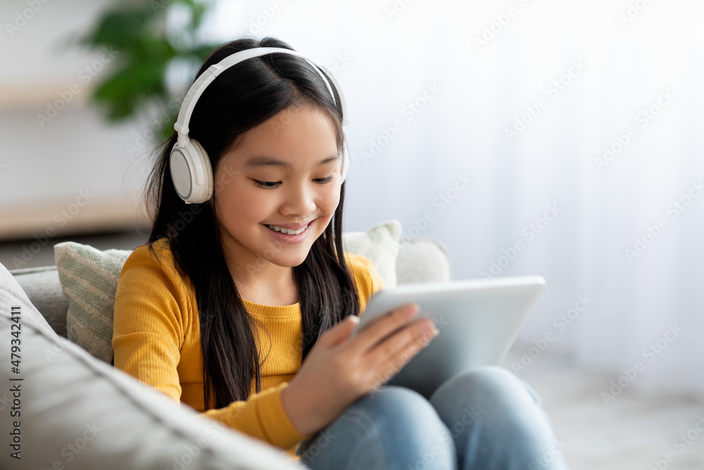 Happy korean girl resting on couch with digital tablet Happy korean girl resting on couch with digital tablet