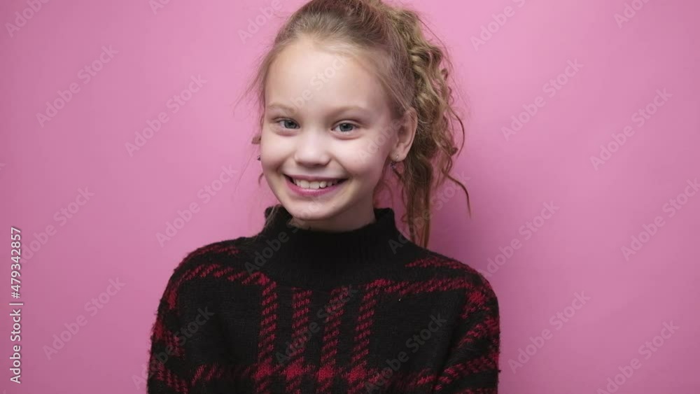Vidéo Stock Portrait of upset little preteen girl looking at camera then smiling on pink background. Sad kid becomes happy | Adobe Stock 