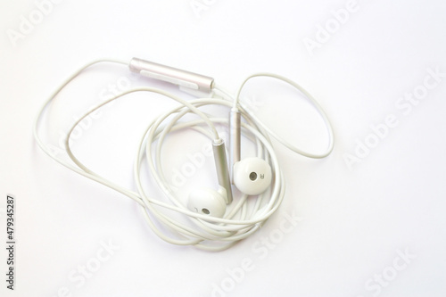 White headphones lie on a white background. Audio concept, listening to music on the go or mobile accessory.