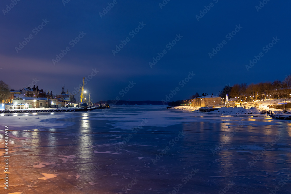 The port of Vyborg at night in winter with frozen water in the bay.