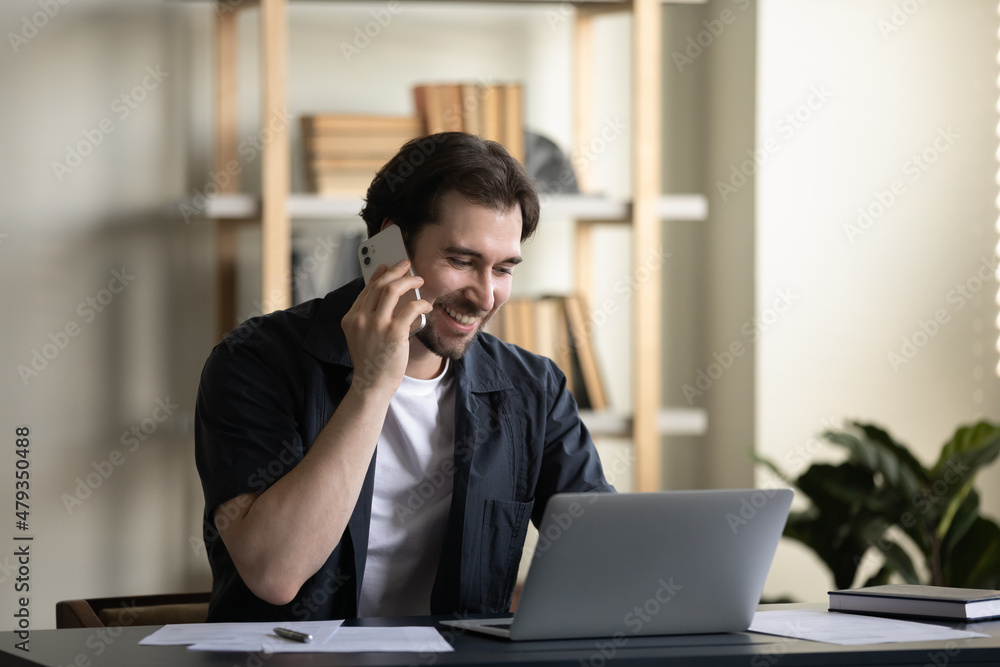 Happy friendly young businessman manager employee involved in phone call conversation, consulting client or discussing project with partner, multitasking working on computer in modern home office, Happy friendly young businessman manager employee involved in phone call conversation, consulting client or discussing project with partner, multitasking working on computer in modern home office,