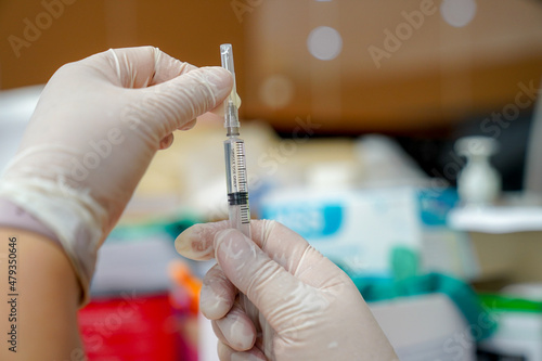 Doctor filling syringe with Covid-19 vaccine doctor or scientist in the COVID-19 medical vaccine research and development laboratory holds a syringe with a liquid vaccine to study.