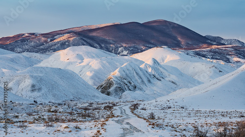 Dirt road to snow covered mountains. Winter landscape