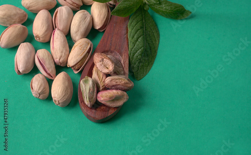 Pistachios or Pista nuts decorated with green leaves. plain background, top view.Flat lay.
 photo