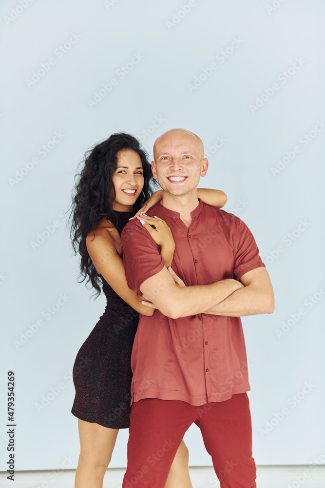 Standing in the studio against white background. Cheerful couple is together indoors Standing in the studio against white background. Cheerful couple is together indoors
