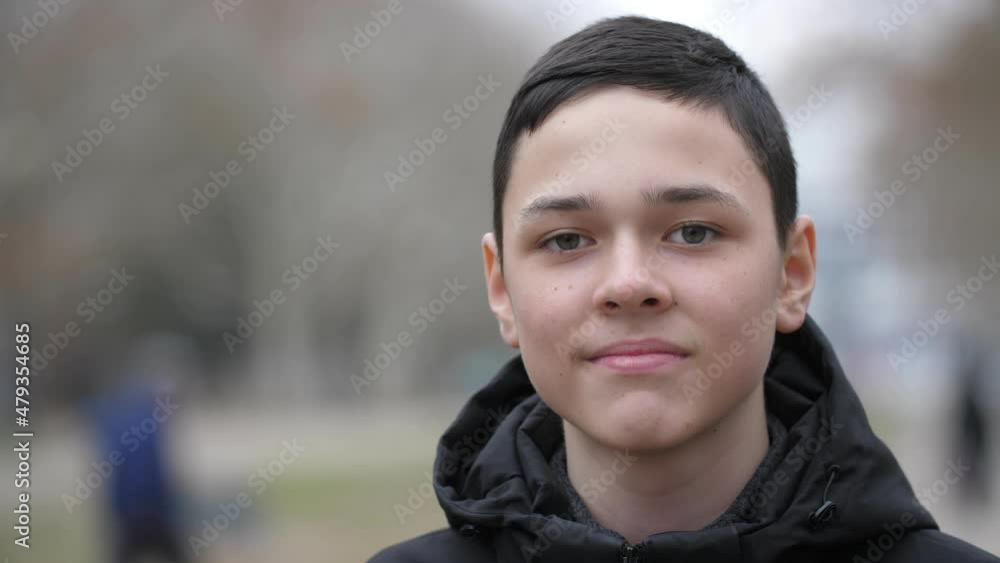 Portrait of a 13-year-old European boy dressed in a black jacket. He stands on the street in autumn and looks at the camera against a blurred background. Slow motion, close-up, shallow depth of field Portrait of a 13-year-old European boy dressed in a black jacket. He stands on the street in autumn and looks at the camera against a blurred background. Slow motion, close-up, shallow depth of field