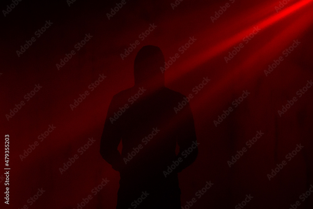 
Silhouette of a man from the back, red rays of light, indoor photo