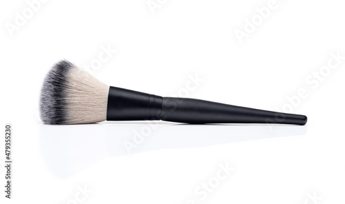 Makeup brush on a white reflective surface and a white background.