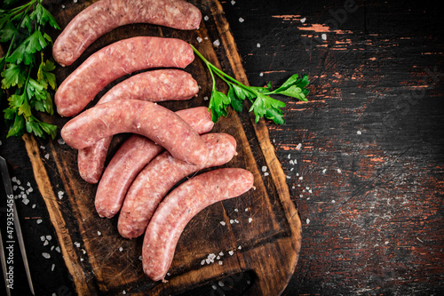 Obraz na plátně Raw sausages on a cutting board with parsley