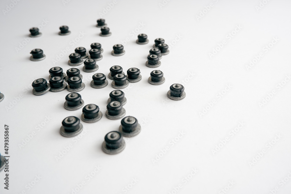 Repair of winter studded tires. Repaired spikes scattered on a white background. Replaced lost car tire spikes. Repair of winter studded tires. Repaired spikes scattered on a white background. Replaced lost car tire spikes.