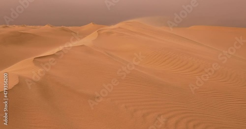 Strong wind at sunset over the sand dunes in the desert. Sandstorm in the Desert photo