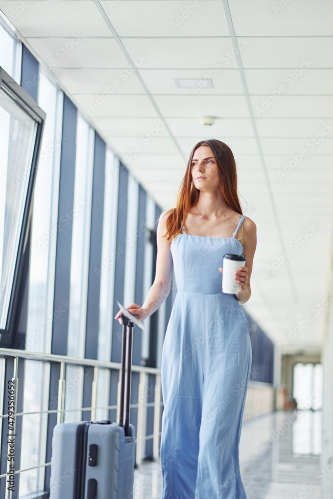 Woman holding coffee. Young traveler is on the entrance hall in the airport