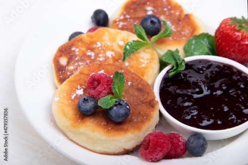 Cottage cheese pancakes with berries on a white plate on the table