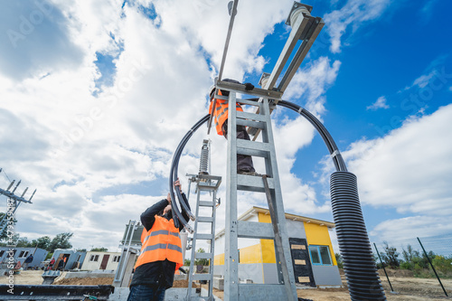 Two electrician builder workers installing high-voltage cable