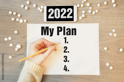 My plan - writing in notebook with white phone 2022, concept for new year resolutions plan. Beginning new bussiness year. photo