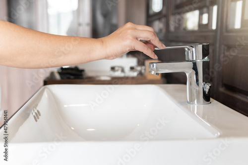 Close up Woman open chrome faucet washbasin to washing hands rubbing with soap for corona virus at water tap Faucet and water drop off. Bathroom interior with sink basin and water tap. Tap water down.