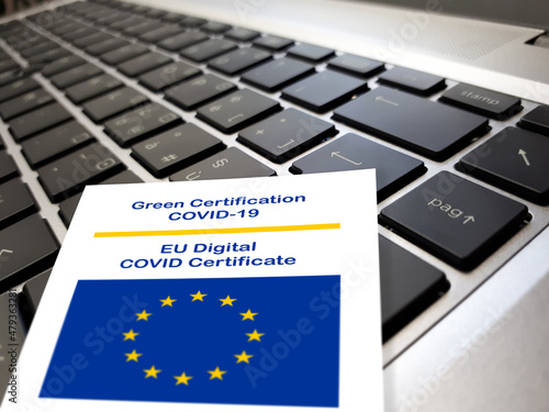 Close-up of the Green Certificate Covid-19 of the European Union paper on the keyboard of a notebook. photo