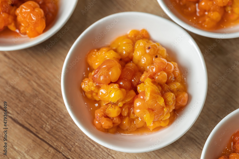 Juicy ripe cloudberry northern in a plate. Many plates on the table. Juicy ripe cloudberry northern in a plate. Many plates on the table.