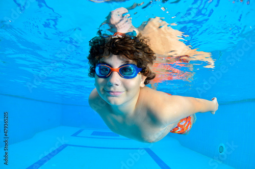 Young Boy Fun Underwater In Swimming Pool With Glasses. Summer Vacation Fun.