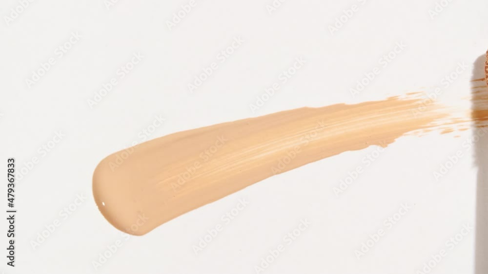Macro shot and slow motion of a brush, applicator, smear, concealer isolated on white background. Advertising professional cosmetics. Closeup of a cosmetic liquid foundation or cream beige color. 4k Macro shot and slow motion of a brush, applicator, smear, concealer isolated on white background. Advertising professional cosmetics. Closeup of a cosmetic liquid foundation or cream beige color. 4k