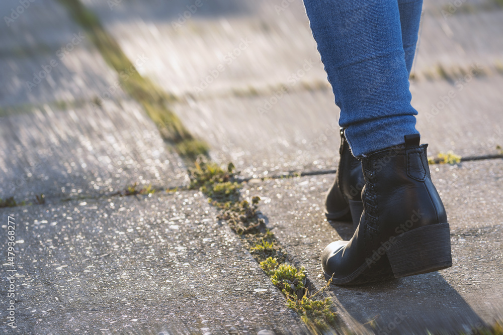 Woman walking forward in the park, moving feet in leather boots at sunset. Leisure activity, walking concept Woman walking forward in the park, moving feet in leather boots at sunset. Leisure activity, walking concept