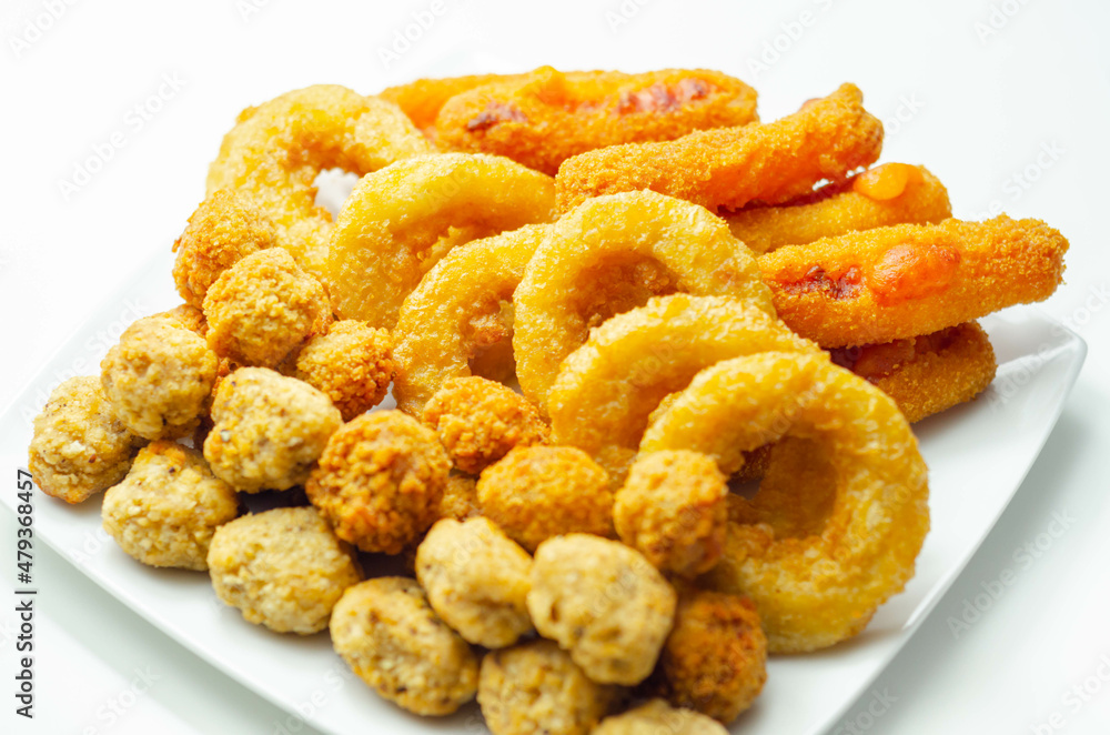 Southern fried and roast chicken bites, onion rings and mozzarella stick served on the white plate Southern fried and roast chicken bites, onion rings and mozzarella stick served on the white plate