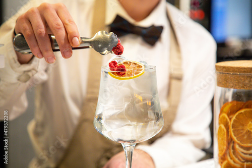 mixologist decorating a vodka and tonica cocktail in a restaurant bar photo