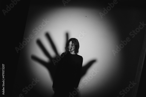 Girl and the shadow of a hand on the wall. Black and white photo of a girl.