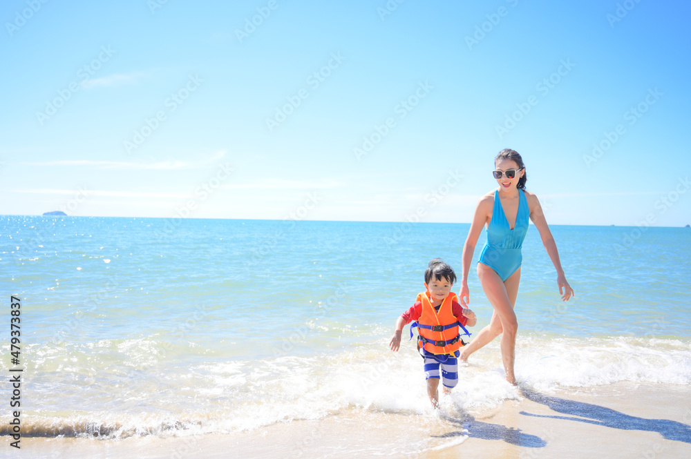 Mother and baby boy waer life vest at the beach